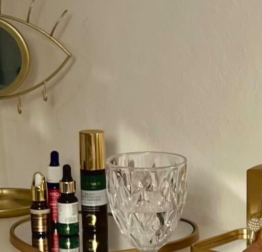 Detalhe da bancada: bandeja dourada com séruns e ativos, taça de cristal e difusor de ambiente.